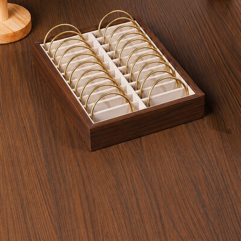 Wooden jewelry display box with gold rings on a wooden surface