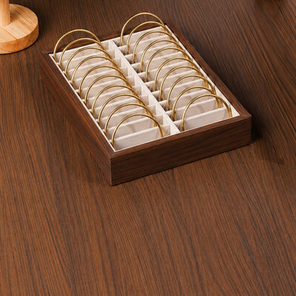 Wooden jewelry display box with gold rings on a wooden surface